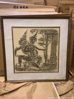 Full view of framed rubbing art showing two traditional Southeast Asian figures and part of a temple structure.