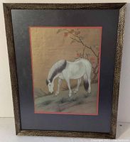 Front view of framed vintage Chinese horse print. Shows horse with black mane grazing next to flowering branch, framed in textured brown frame with dark matte and red border around print.