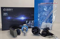 Fahren LED Car Lighting Kit components displayed outside box on blue background, including bulbs, black mounting parts, wiring adapters, and plastic installation pieces in bag.