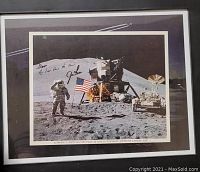 Framed black and white photo showing astronaut Irwin saluting the American flag on the moon at Apollo 15 Hadley-Apennine site with lunar module and rover. Photo signed.