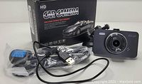 Full HD car camera dash recorder with accessories including USB cable and car power charger, displayed outside of box.