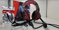 Hunterspider V-3 pro gaming headset with red and black design, packaged box, attached mic, and sound splitting cord accessory in sealed bag.