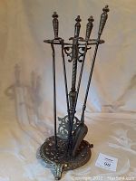 Full view of the antique brass fireplace tool set on stand, showing four pieces with ornate handles and decorative brass stand.