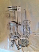 Full shot showing the metal corner caddy, wire frame toilet paper holder, and wall mounted swivel mirror against a plain backdrop