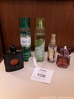 All five fragrance items shown together on white surface against wood panel background.