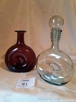 Pair of glass decanters on table, clear and reddish-purple colors visible