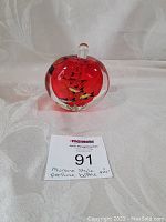 Front view of the red Murano style perfume bottle with internal floral design and stopper on top.