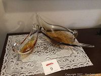 Two glass gondola-shaped centerpiece bowls placed on a lace doily, showing both items from a front angle.