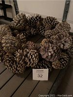 Front view of natural pine cone Christmas wreath with gold glitter, showing dense pine cone arrangement and size relative to MaxSold card.