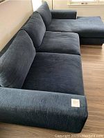 Angle view of navy blue sectional sofa with chaise, showing arm and seat cushions