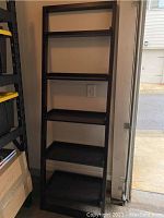 Front view of the dark brown leaning bookshelf with five shelves, showing condition and structure.
