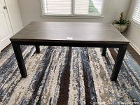 Full view of rectangular Mid Century modern dining table showing wood top and black metal legs.