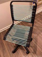 Front view of office chair showing black frame and mint green bungee cords forming seat and backrest.