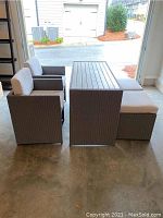 Front view of assembled table with two armchairs and two ottomans with cushions arranged inside garage