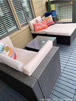 Full view of two wicker lounge chairs, ottoman and glass-top table on deck
