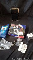 View of all lot items including Valvoline CVT oil, wheel accessories box, car door locks with keys, black box, and cup holder.