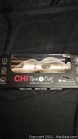 Front view of the CHI Spin N Curl curler in its original box with black and clear plastic window and brand logo visible.