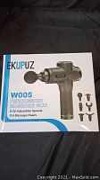 Box front showing brand Ekupuz model W005 percussion massage gun with image and accessories.