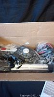 Photo of the boxed RoomieTEC mini cordless vacuum components including wand, main vacuum body, and accessories in plastic wrapping.