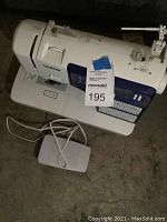 Front view of used Brother sewing machine showing stitch pattern panel and attached foot pedal on floor.