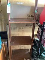 Front view of brown wooden leaning bookshelf featuring four shelves, showing overall structure and condition.