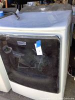 Front view of Maytag gas dryer showing black glass door and white frame with Maytag logo.