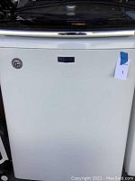 Front view of white Maytag washing machine with logo and badge visible on front.