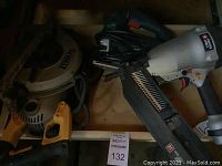 Shelf containing yellow/black DeWalt circular saw and silver/black Porter Cable pneumatic framing nailer.