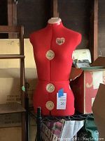 Red fabric-covered tailor's dress form mannequin torso with adjustable dials on bust, waist, hips. Size marked 150.