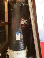 Black punching bag with Ringside logo, hanging in a corner with metal rings visible at top.