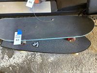Top and bottom view of the two skateboards stacked, showing grip tape, deck color and wheels.