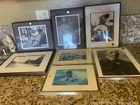 Six framed art prints including black and white and color photos arranged on granite countertop.