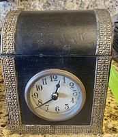 Black clock box with silver decorative trim and built-in clock on front