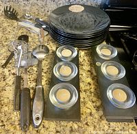 Black plates stacked and displayed with candle holders and utensils on countertop