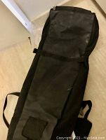 Photo of one black ski bag, long in length, with strap and buckle visible for securing contents.