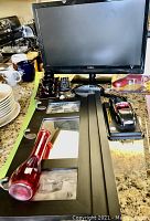 Image showing all items in the lot including the Insignia TV, model car, black framed mirror, hand mirror, light set, and paper holder stand arranged on countertop.