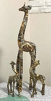 Set of three wooden giraffe figurines of varying sizes with animal print designs, placed on a table