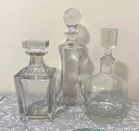 Three vintage heavy glass or crystal decanters, tallest one labeled Villeroy & Boch with round stopper, other two smaller unbranded with square or rectangular stoppers.