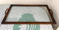 Full view of the rectangular wood and glass serving tray showing rectangular shape, wooden frame, transparent glass center, and side handles.