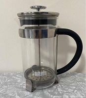 Front angled view of a Bialetti French press showing glass carafe, stainless steel top and plunger, with black ergonomic handle.