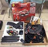 Photo shows Carrera GO!!! Ferrari F1 Masters box behind open box with collection of track pieces, controllers, slot cars, and accessories.