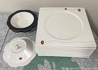 Set of 11 square dinner plates stacked and 4 bowls stacked showing shape and design