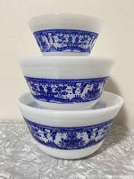 Front view of the three nested white glass bowls with Blue Willow design.