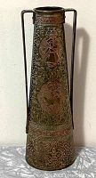 Full view of tapered etched brass vase showing overall shape with two vertical handles and intricate medallion figural scenes.