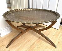 Full view of brass tray seated on wooden X-frame folding base