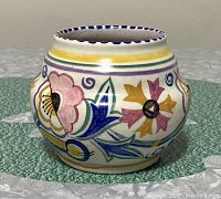 Front and side view of a colorful round hand painted pottery vase with floral patterns.