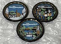 Three vintage Walt Disney World glass coasters arranged on a surface, showing colorful scenes from Liberty Square, Donald Duck and nephews, and Adventureland.