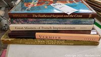 Stack of six art and map books seen from above, showing titles on spines.
