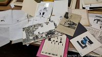 Photo showing assorted art student drawings laid out including sketches of figures, animals, and surreal scenes in ink and pencil.