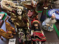 Top view showing all dolls and figurines including crouching tiger figures, angel figurine, two porcelain dolls, and other assorted figurines arranged on table.